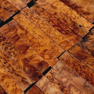 May include: Close-up of several rectangular wooden blocks with a rich, warm brown color and intricate grain patterns. The wood has a polished appearance, with darker and lighter areas creating visual interest. The blocks are arranged in a diagonal pattern.