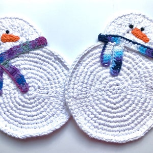 May include: Two white crocheted snowman ornaments with colorful crocheted scarves. The snowman on the left has a purple, blue, and green scarf. The snowman on the right has a blue, purple, and black scarf.
