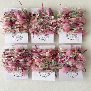 May include: Six spools of pink, white and green yarn with a label that says "Three Blue Larks".