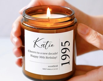 May include: A brown glass candle with a white label that reads "Katie 1995 Cheers to a new decade! Happy 30th Birthday!" and "scentfield SWEET VANILLA 9.0 OZ".
