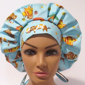May include: A light blue surgical scrub hat with a pattern of sloths on surfboards and palm trees. The hat has a tie at the back.