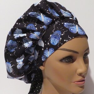 May include: A black scrub hat with a blue and white butterfly pattern. The hat has a black and white polka dot tie.