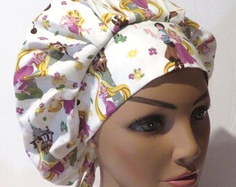 May include: White bouffant scrub cap featuring a repeating pattern of a princess with long blonde hair, a prince, and other fairytale elements. The cap has a tie closure and is designed for medical professionals or those in the beauty industry.