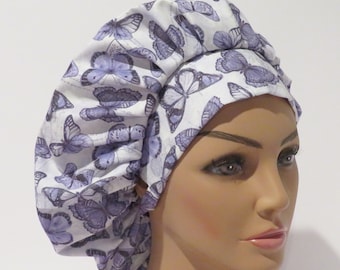 May include: A white surgical scrub cap with a purple butterfly print. The cap is made of a soft, comfortable fabric and has a tie at the back.