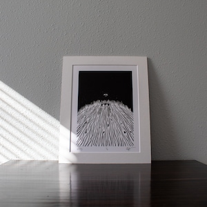 May include: Black and white print of a landscape with a dark sky and a field of tall grass. The print is framed in a white frame and has the word "void" printed in the bottom left corner.