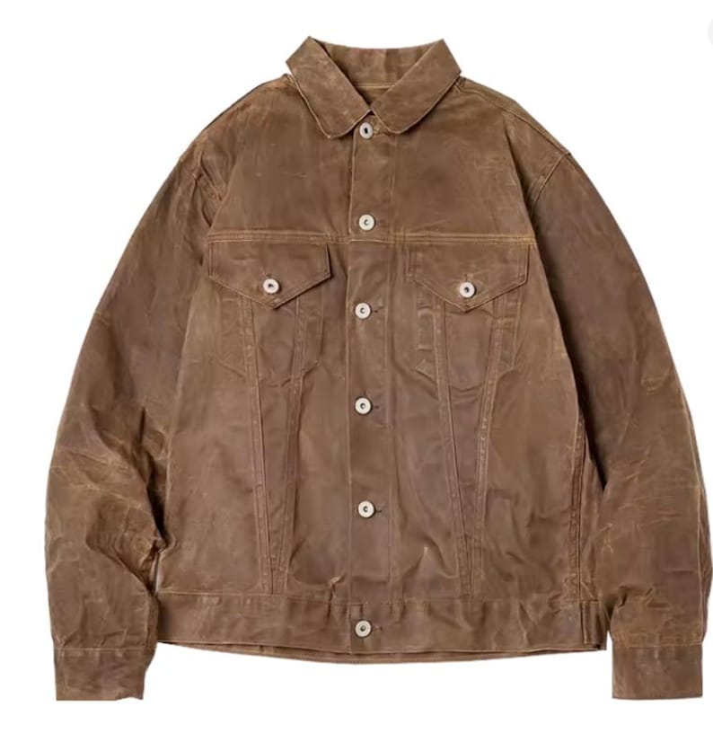 May include: A brown waxed cotton jacket featuring a classic collar, two chest pockets, and button fastenings. The jacket has a slightly worn appearance, suggesting a vintage or rugged style. The jacket is a versatile outerwear piece.