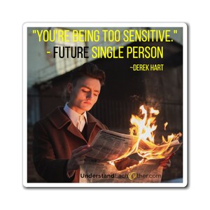 May include: A sticker with a quote: "YOU'RE BEING TOO SENSITIVE." - FUTURE SINGLE PERSON ~DEREK HART. The image shows a person holding a burning newspaper. The website UnderstandEachOther.com is at the bottom.