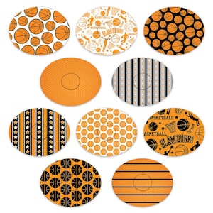 May include: Ten round orange and black basketball themed coasters with various designs. Some designs include basketballs, stars, stripes, and the words "Slam Dunk" and "Basketball".