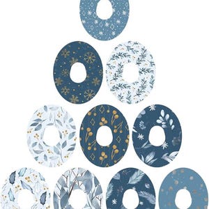 Puede incluir: Conjunto de diez pegatinas redondas azules y doradas con un agujero en el centro. Los patrones incluyen copos de nieve, hojas, bayas y formas geométricas.