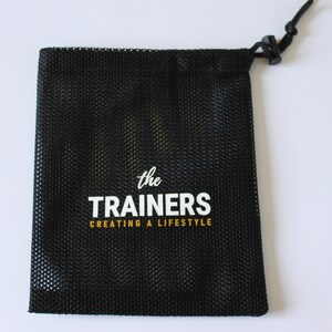 Puede incluir: Bolsa de cord&oacute;n de malla negra con texto blanco que dice "the TRAINERS creating a lifestyle"