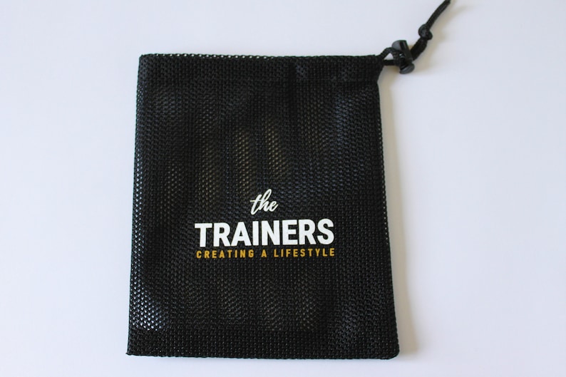 Puede incluir: Bolsa de cord&oacute;n de malla negra con texto blanco que dice "the TRAINERS creating a lifestyle"
