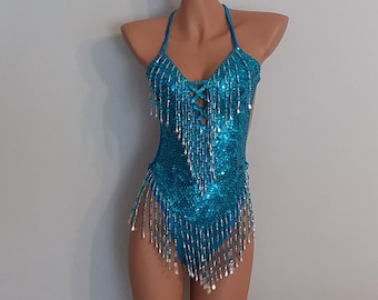 May include: A turquoise sequined bodysuit with a halter neckline and beaded fringe. The bodysuit is on a mannequin.