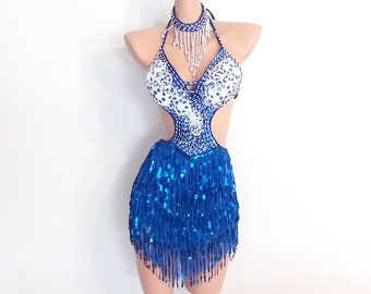 May include: A blue and white dance costume with a halter top and a skirt with fringe. The top is embellished with rhinestones and the skirt has a sequined fringe. The costume is displayed on a mannequin.
