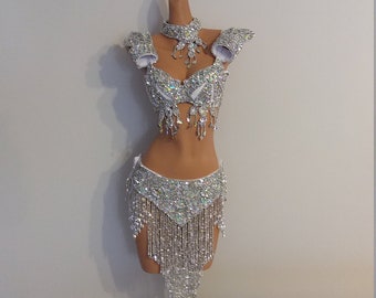 May include: A silver sequined costume with a halter top, a skirt with fringe, and a matching necklace. The costume is on a mannequin.