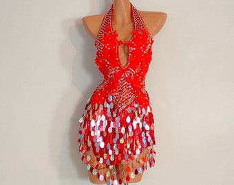 May include: A red sequined halter dress with a plunging neckline and a skirt made of iridescent sequins. The dress is on a mannequin.