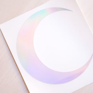 May include: A white sticker with a crescent moon design. The moon is iridescent with a rainbow of colors.