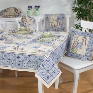 Pode incluir: Uma mesa branca com uma toalha de mesa estampada em azul e branco. A toalha de mesa apresenta um desenho de flores de lavanda e azulejos. Há duas cadeiras brancas com um almofada estampada em azul e branco em uma das cadeiras.