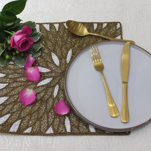 Op de afbeelding: Een wit bord met gouden bestek op een gouden en witte parel placemat. Roze rozenblaadjes zijn rondom de placemat gestrooid.