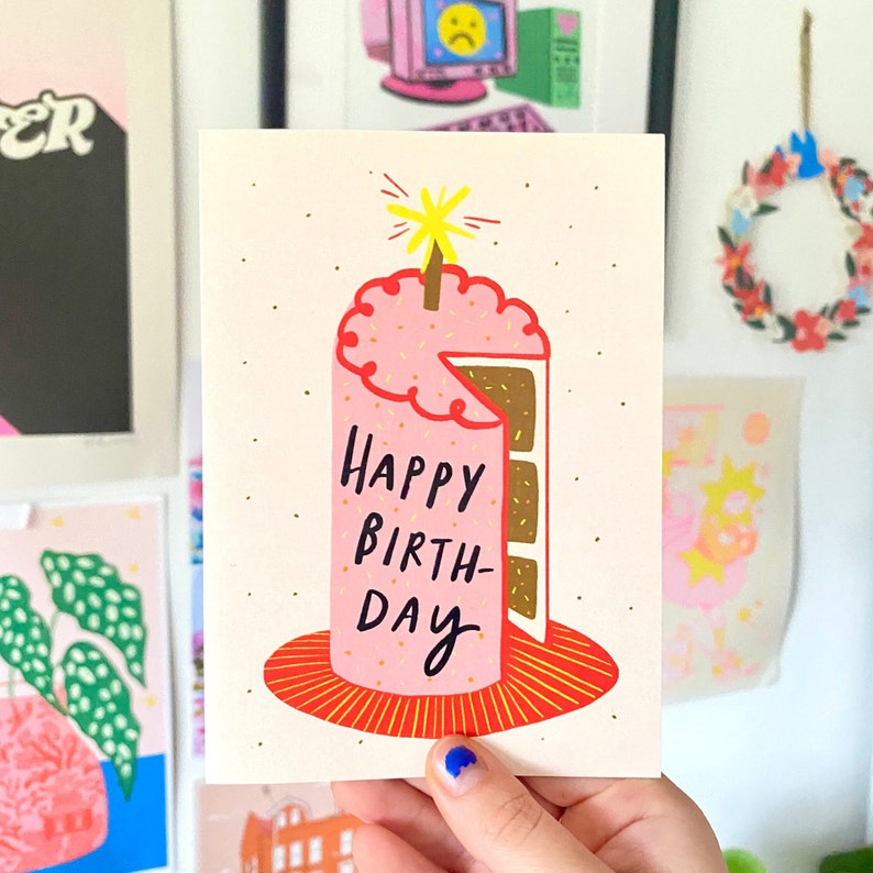 hand holding birthday card pink cake with candle reading happy birthday blank inside