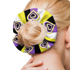 May include: A purple, black, and yellow scrunchie with a heart pattern. The scrunchie is made of fabric and has a stretchy band.