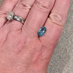 K&ouml;nnte beinhalten: Ein hellblauer ovaler Edelstein auf einer Hand.