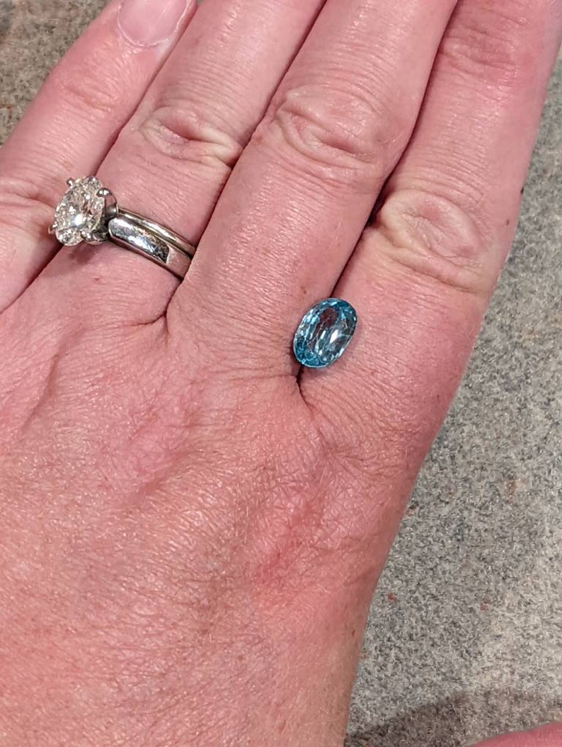 K&ouml;nnte beinhalten: Ein hellblauer ovaler Edelstein auf einer Hand.