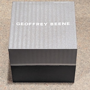 May include: A gray and black box with the text "GEOFFREY BEENE" printed on the top.