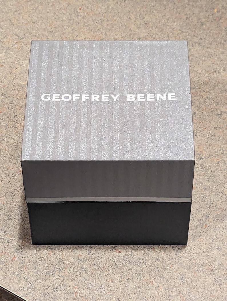 May include: A gray and black box with the text "GEOFFREY BEENE" printed on the top.