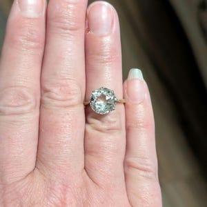 May include: A gold ring with a large, clear, faceted gemstone.