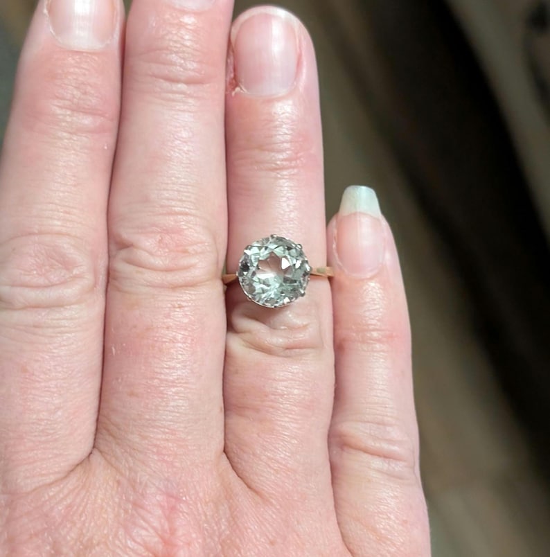 May include: A gold ring with a large, clear, faceted gemstone.