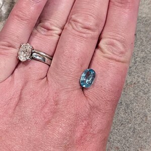 K&ouml;nnte beinhalten: Ein ovaler, hellblauer Edelstein mit Facetten auf einer Hand.