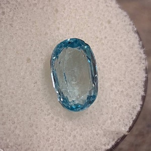 K&ouml;nnte beinhalten: Ein ovaler, hellblauer Edelstein mit einem leichten Schimmer.