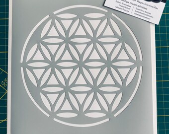 May include: A gray reusable adhesive stencil featuring a white flower of life design. The stencil is 100% adhesive and repositionable. The text "www.pochoirsdeco.fr" is printed in the top right corner of the stencil.