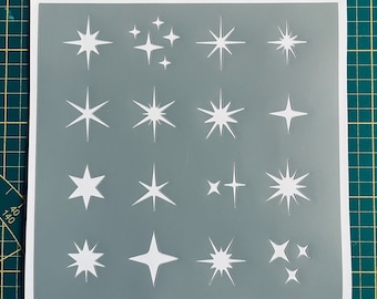 Op de afbeelding: Een witte stencil sheet met 16 verschillende stervormen uitgesneden. De stencil is op een grijze achtergrond.