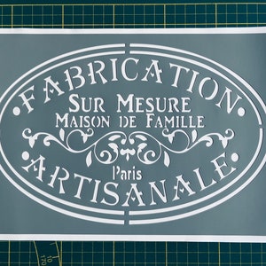 Puede incluir: Una plantilla gris con letras blancas que dicen "Fabrication Sur Mesure Maison de Famille l'aris Artisanale".