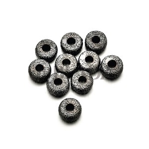 Op de afbeelding: Tien zwarte metalen afstand kralen met een getextureerd oppervlak. De kralen zijn rond met een gat in het midden.