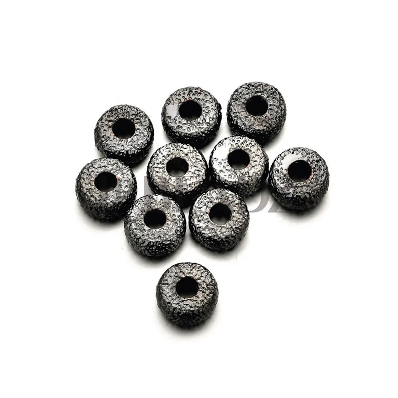 Op de afbeelding: Tien zwarte metalen afstand kralen met een getextureerd oppervlak. De kralen zijn rond met een gat in het midden.