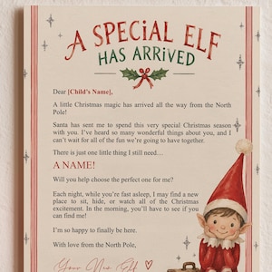 May include: A matte red Christmas bauble next to a rectangular card titled A SPECIAL ELF HAS ARRIVED. The card features a printed letter from an elf, a small illustration of an elf in a red hat and striped stockings, and a brown suitcase.