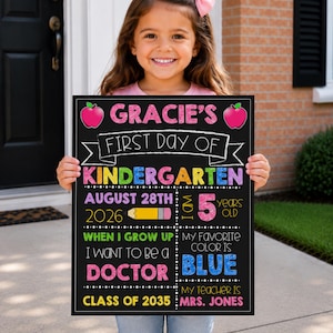 Op de afbeelding: Een rechthoekig krijtbord met een zwarte achtergrond en kleurrijke tekst. Er staat op: Gracie's First Day of Kindergarten, August 28th 2026, I am 5 years old, When I grow up I want to be a doctor, My favorite color is blue, Class of 2035, Mrs. Jones.