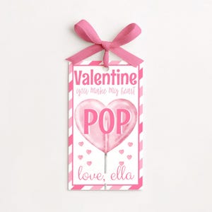 May include: A Valentine's Day gift tag with a pink bow at the top. The tag features a pink heart-shaped lollipop with the word "POP" in the center. The text "Valentine you make my heart" is above the lollipop, and "love, ella" is below.