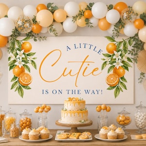 May include: A baby shower display featuring a sign saying "A Little Cutie Is On The Way!" The table is laden with a two-tiered cake, cupcakes, cake pops, and other treats, all decorated with oranges and orange accents. Balloons and floral arrangements add to the celebratory atmosphere.