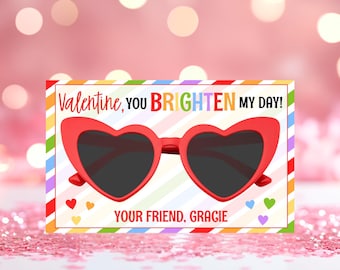 May include: A colourful Valentine's Day card featuring a red heart-shaped sunglasses graphic. The card reads "Valentine, you brighten my day!" and "Your friend, Gracie".