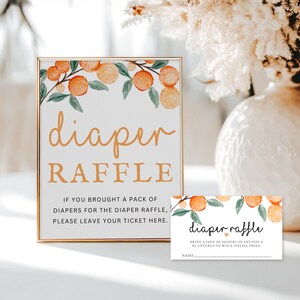 K&ouml;nnte beinhalten: Ein Schild mit goldenem Rahmen und orangefarbenem Blumendesign lautet "diaper raffle".  Das Schild sagt "Wenn Sie eine Packung Windeln f&uuml;r die Windeltombola mitgebracht haben, hinterlassen Sie bitte Ihr Ticket hier."  Eine kleinere Karte mit orangefarbenem Blumendesign lautet "diaper raffle" und sagt "Bringen Sie eine Packung Windeln in jeder Gr&ouml;&szlig;e mit und nehmen Sie an der Verlosung eines Sonderpreises teil!" mit einer Zeile f&uuml;r einen Namen.