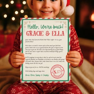 May include: A festive holiday letter held by a child. The letter features a red and green border with the text "Hello, We're back!" and "GRACIE & ELLA." It includes a message from elves, with a stamp that reads "APPROVED BY WORKSHOP ELF."
