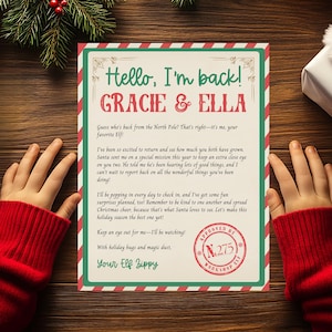 May include: A festive Christmas letter with a red and green border, addressed to Gracie & Ella. The letter includes text from "Your Elf Zippy" and a "Workshop Elf" stamp. The letter is on a wooden surface.