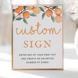 Op de afbeelding: Een wit bord met een gouden lijst en een aquarel-illustratie van sinaasappelbloesems. Het bord zegt "custom SIGN" en "ENTER ANY OF YOUR OWN TEXT AND CREATE AN UNLIMITED NUMBER OF SIGNS!"