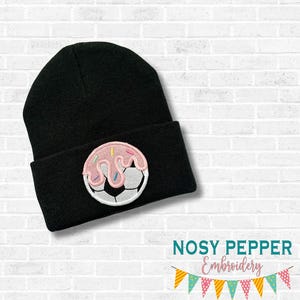 May include: Black beanie hat with a soccer ball and donut design. The hat has a folded cuff and an embroidered patch featuring a soccer ball with pink icing and sprinkles. The text "AUGUST 2025 MEGA BUNDLE" is at the top.