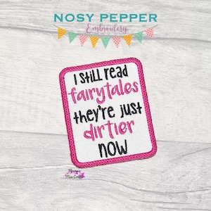 Op de afbeelding: Roze en witte geborduurde patch met de tekst "I still read fairytales they're just dirtier now".