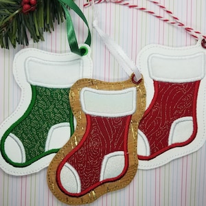 May include: Three Christmas stocking ornaments with white felt trim and different colored felt patterns. The stockings are green, red, and red with a cork background.