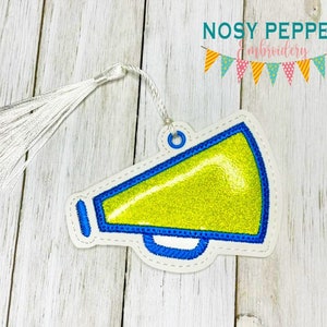 May include: A yellow megaphone with a blue outline and a white tassel. The megaphone is on a white background.